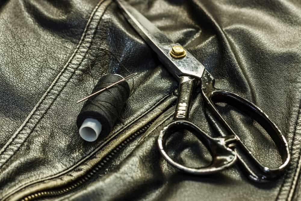皮夹克上面有皮革剪刀和黑色的线和针。