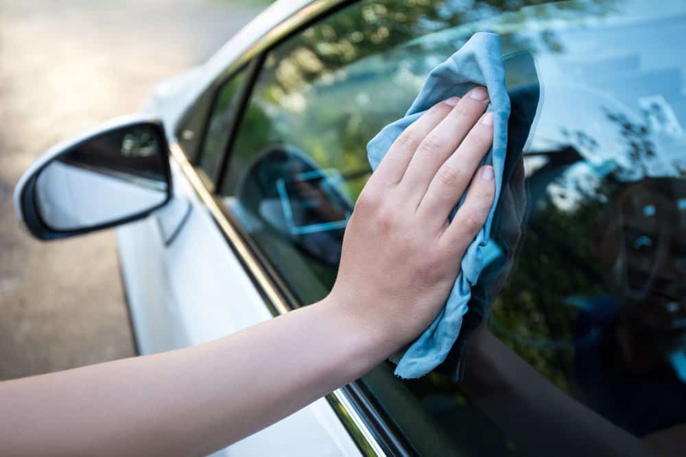 手拿玻璃超细纤维毛巾擦拭车窗。