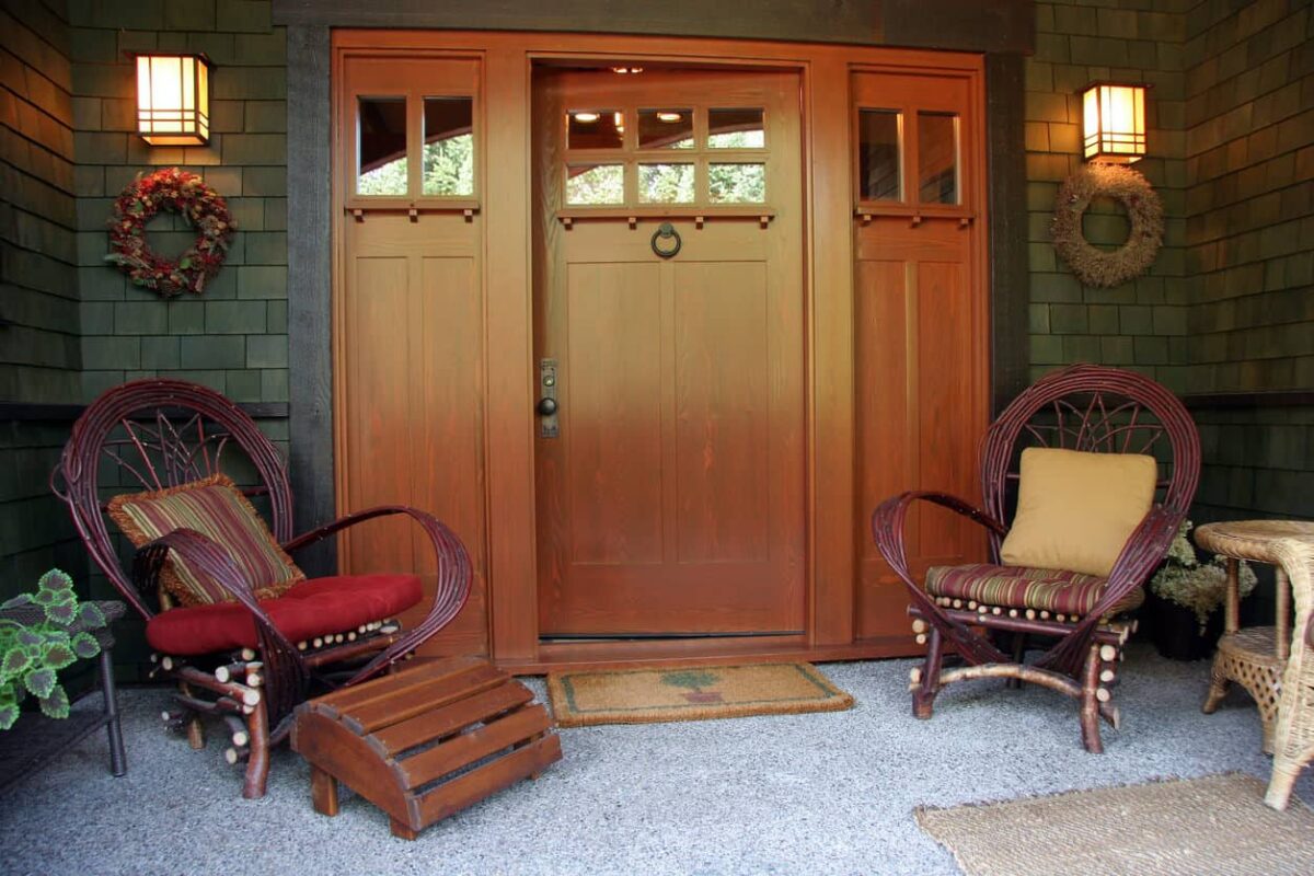 这是一个非常简单的门廊的例子，入口处有两把椅子，两边都有花圈，地板上有地毯和垫子。