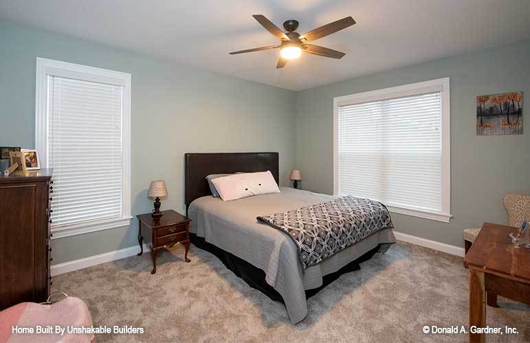 这间卧室配有一张深色的木床、配套的床头柜、一个木制梳妆台和一张桌子。