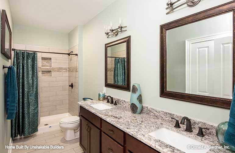 另一间浴室有浴缸和淋浴组合，一个厕所，和双水槽梳妆台搭配框架镜子。
