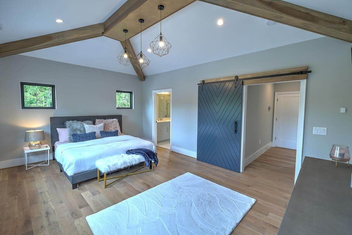 这间卧室铺着硬木地板，有一间私人浴室，还有一扇通向步入式衣橱的大谷仓门。