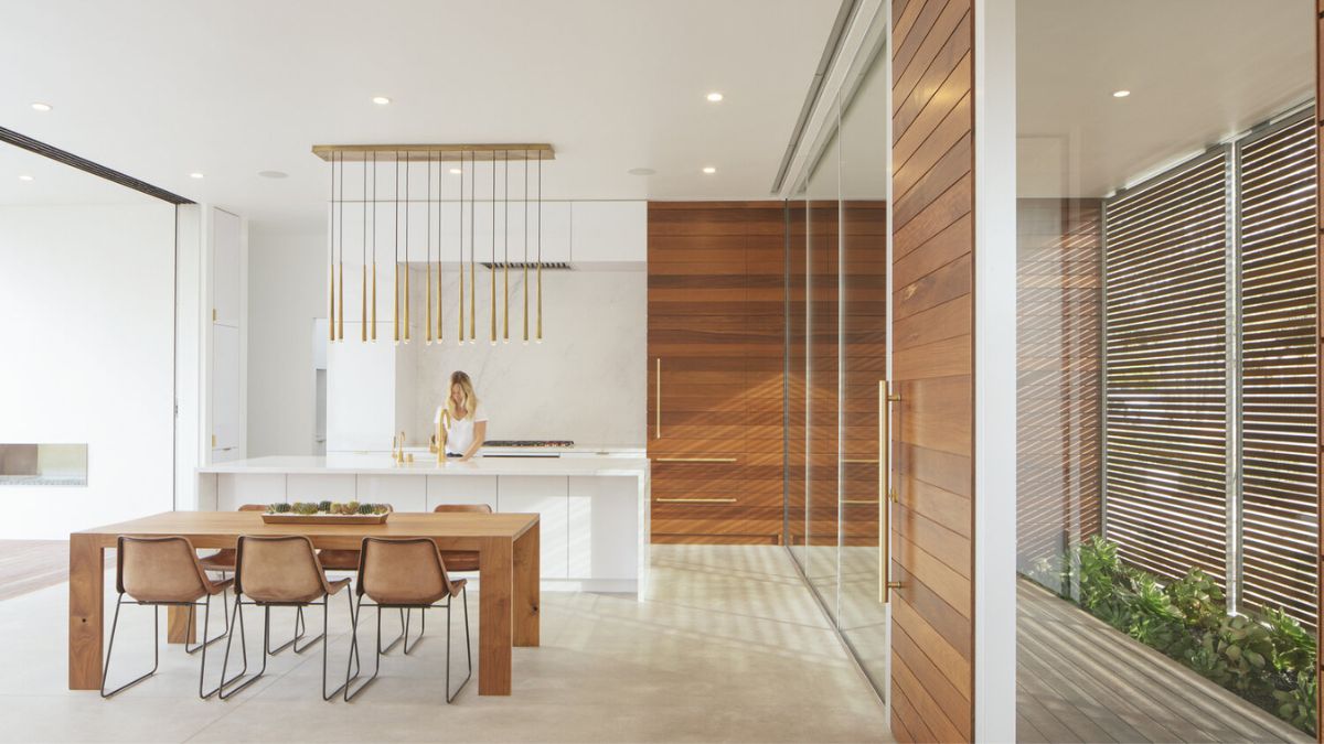厨房和餐厅的照片从客厅的角度,强调简约餐厅设置和厨房的清洁和光滑的设计空间。