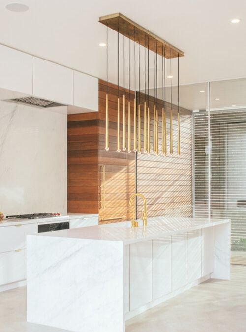 厨房面积的特写照片,凸显了白人厨房的水槽和悬挂灯装饰的主题突出的特性。